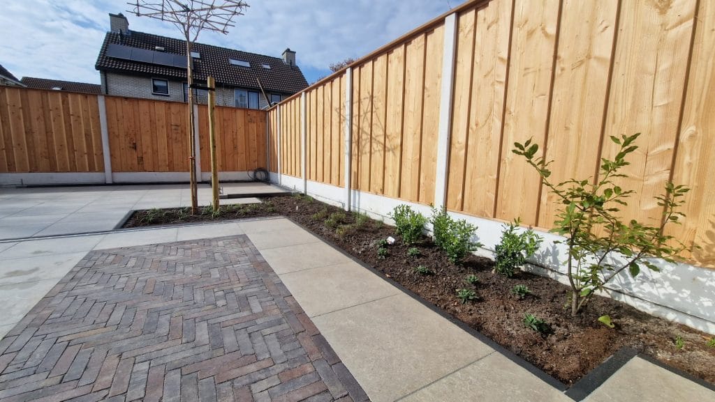 Nieuwe douglas schutting met beplanting en keramische tegels