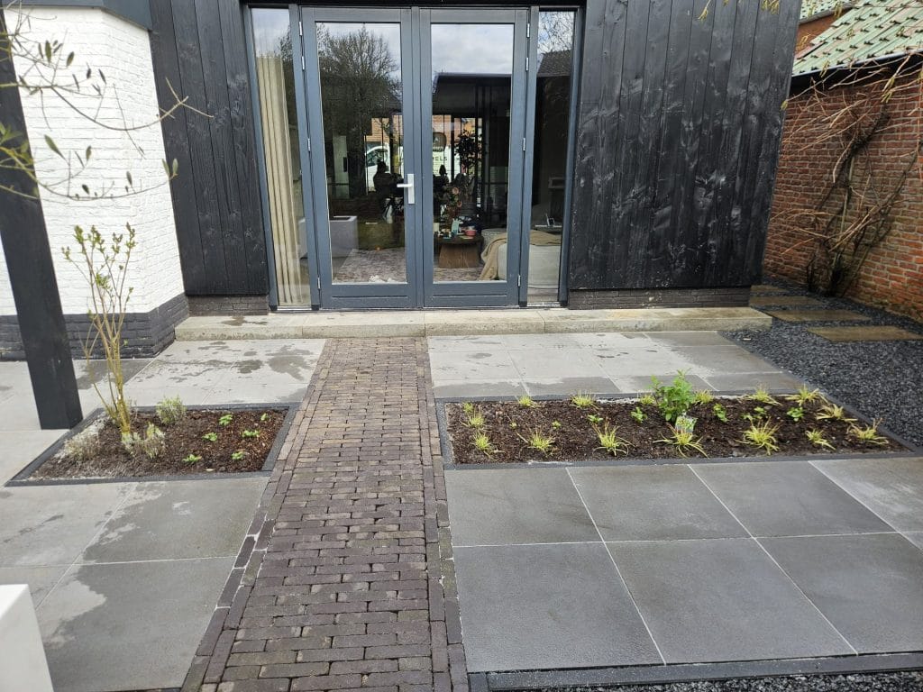 Aangelegde tuin Albergen met zwarte pergola, vers gazon en witte gevel