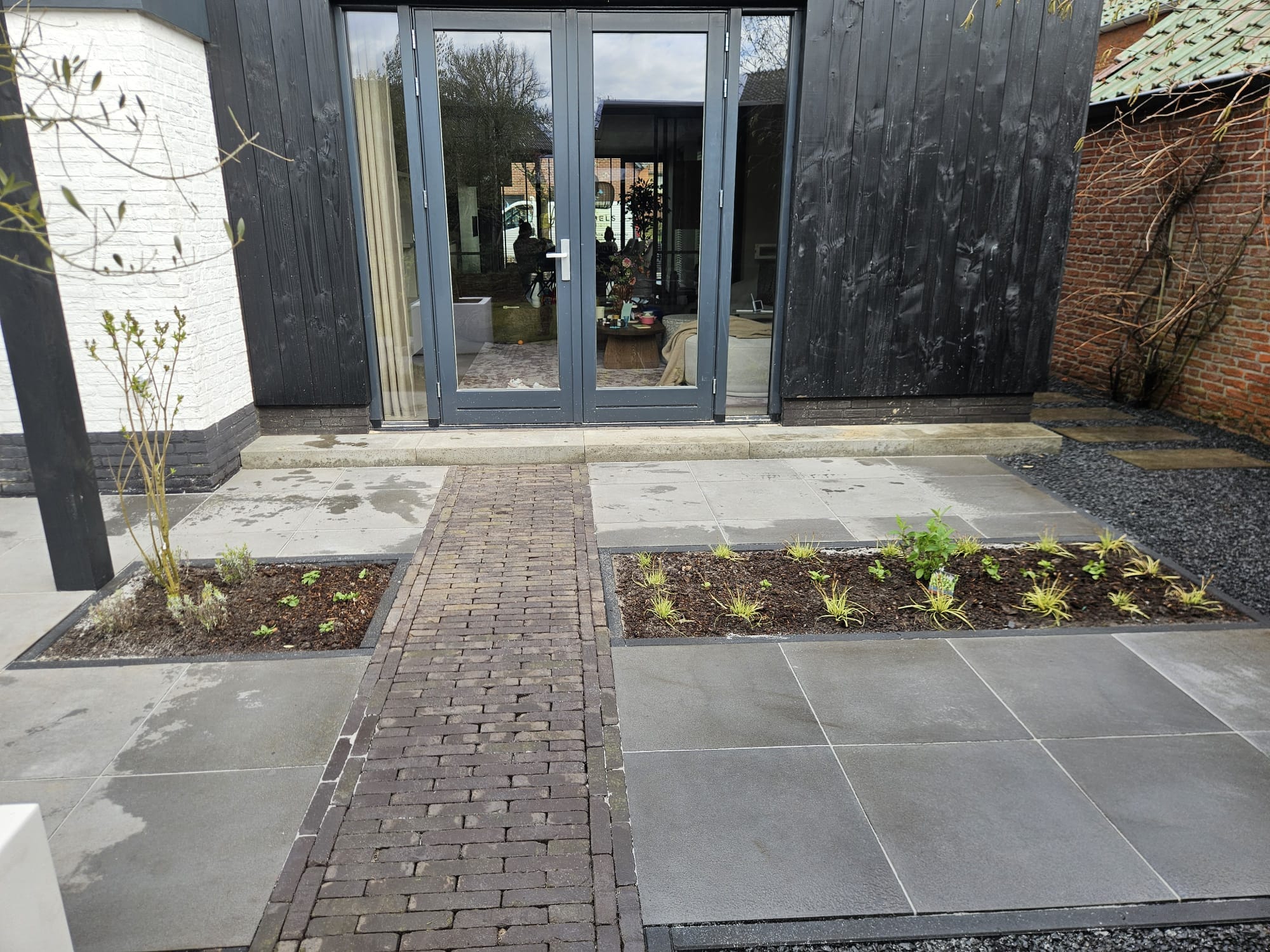 Aangelegde tuin Albergen met zwarte pergola, vers gazon en witte gevel