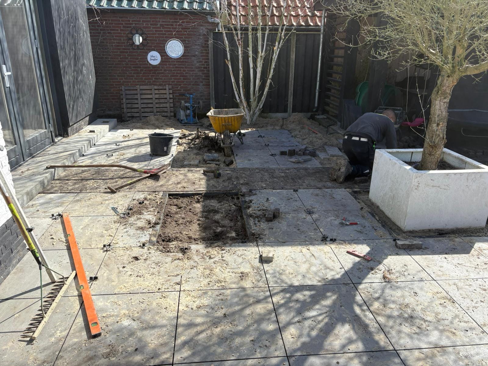 Achtertuin Albergen tijdens aanleg met keramische tegels en witte plantenbak