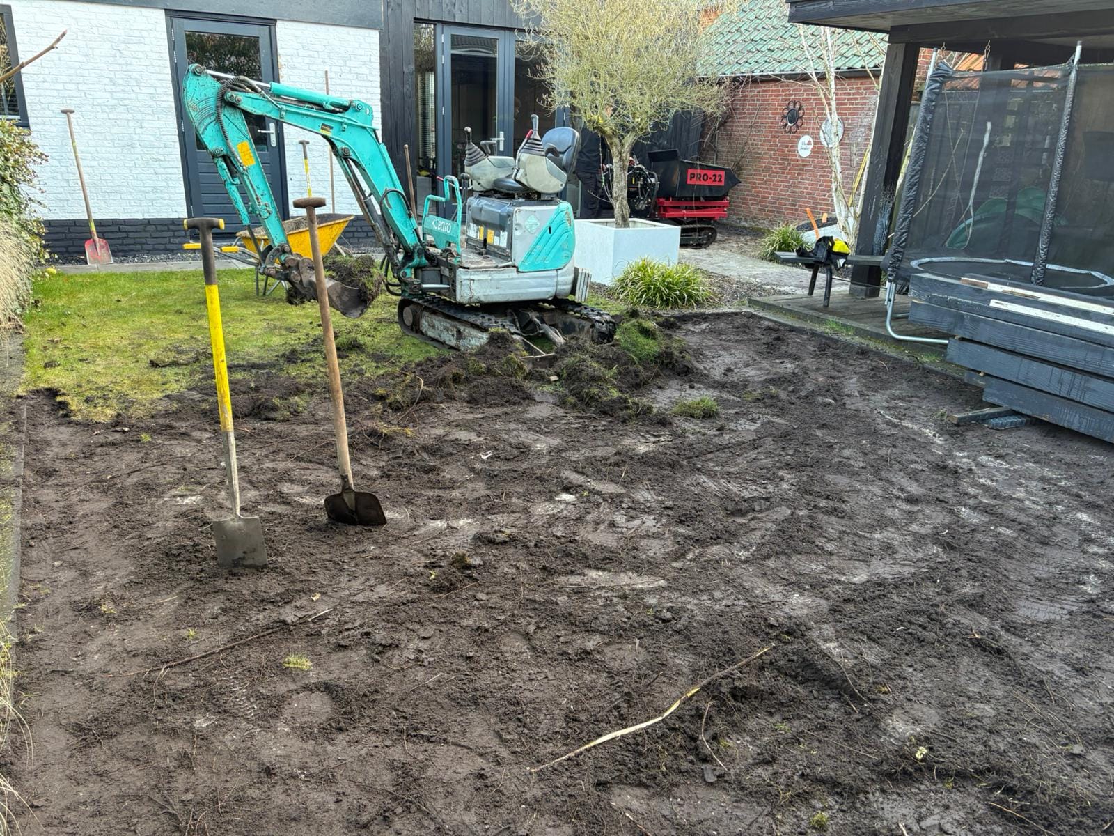 Grondwerk in achtertuin Albergen met minigraver tijdens tuinrenovatie