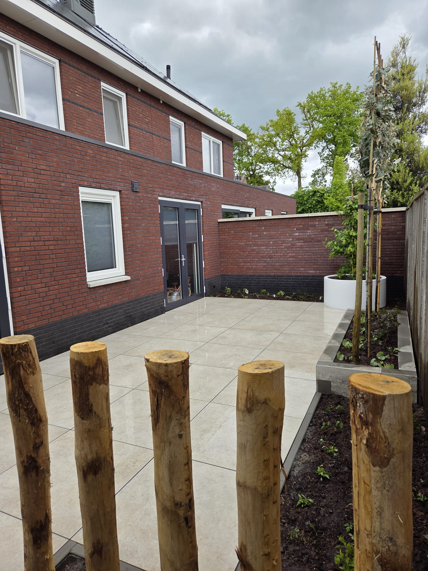 Achtertuin Tubbergen met keramisch terras en kastanjepalen als natuurlijke afscheiding