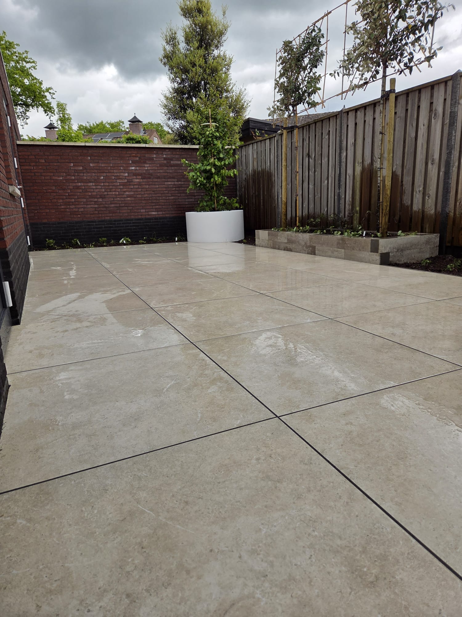 Achtertuin Tubbergen met beige keramisch terras 90x90 en verhoogde border