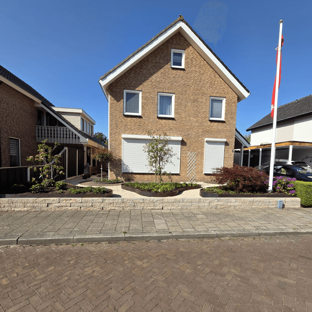Aangelegde voortuin Fleringen met grind, borders en verhoogde splitblokken muur