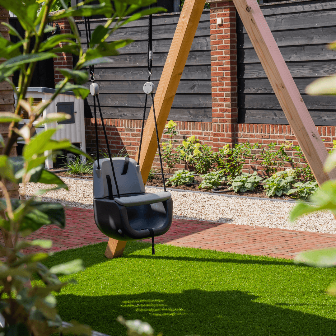 Schommel met kinderzitje boven kunstgras in de tuin bij Erve Tijhuis Langeveen