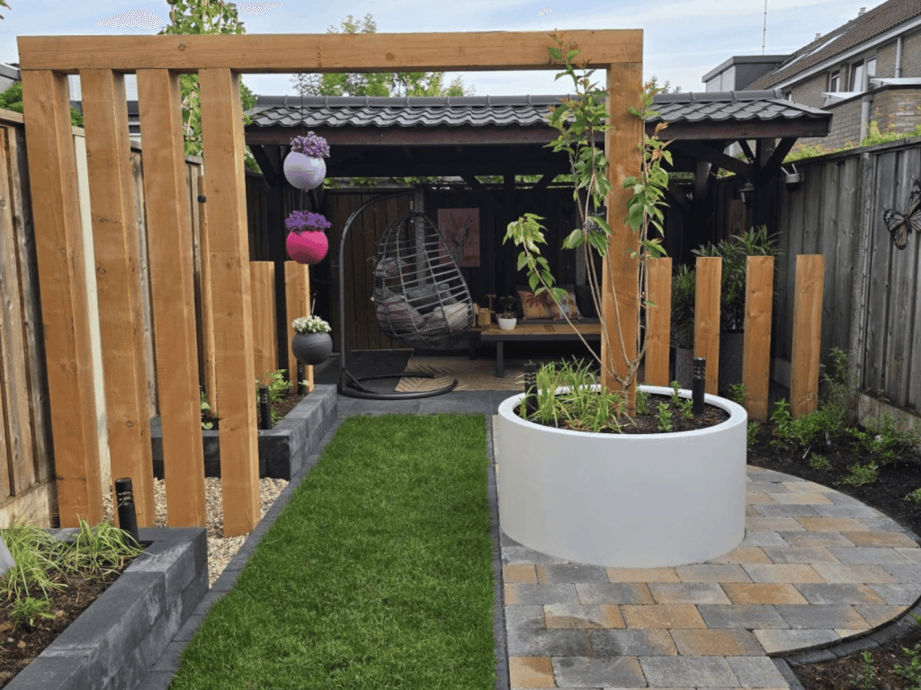 Aangelegde achtertuin De Lutte met douglas afscheidingen, witte plantenbak en Tambour klinkers