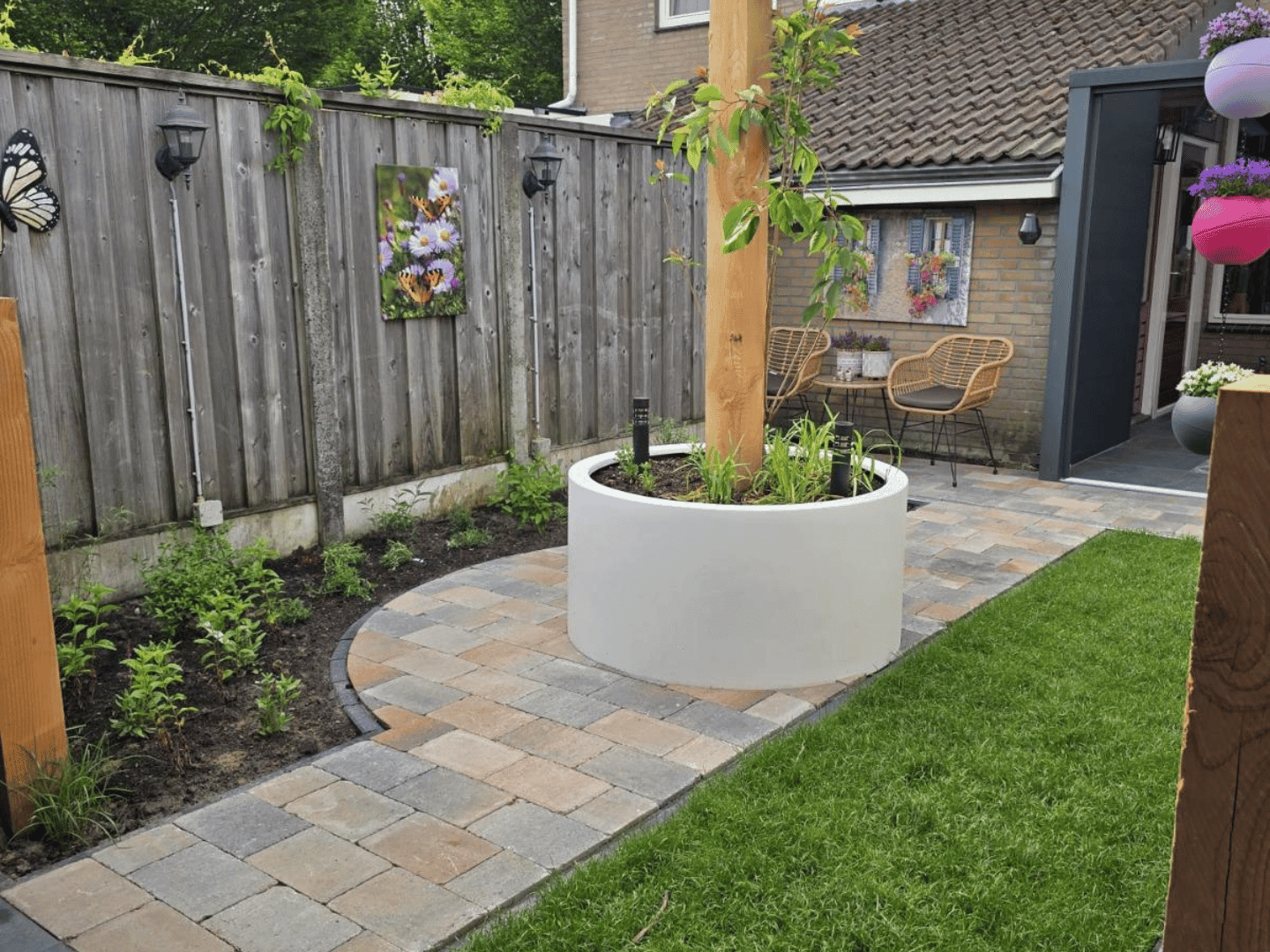 Achtertuin De Lutte met gebogen klinkerpad, verse beplanting en strook gazon