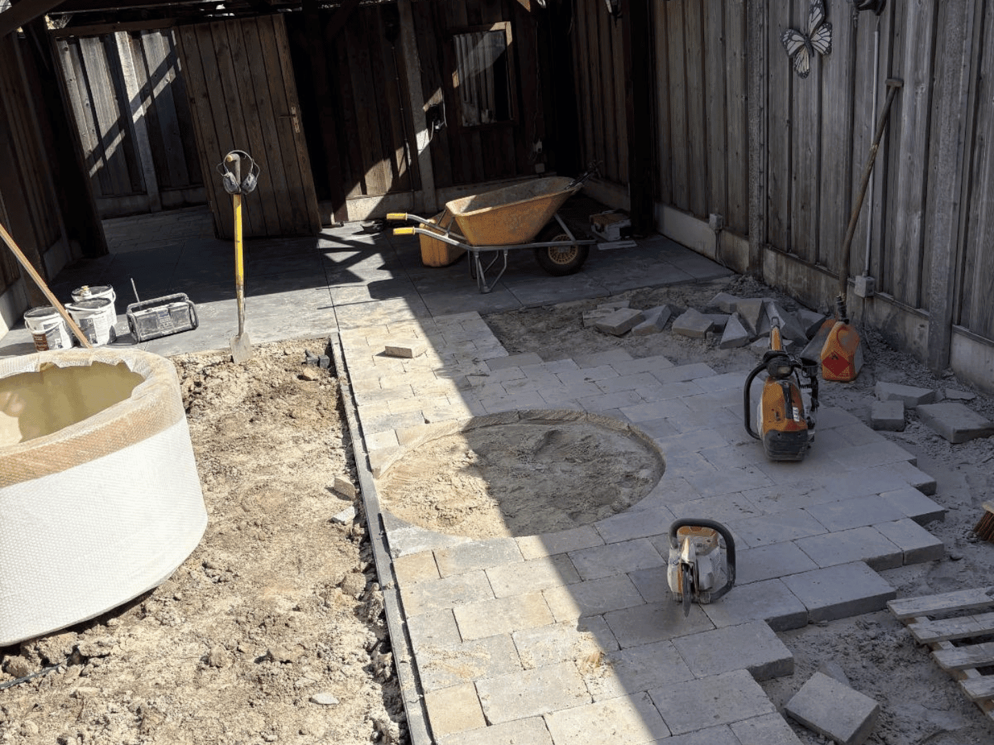 Aanleg straatwerk met Tambour klinkers rond witte plantenbak in achtertuin De Lutte