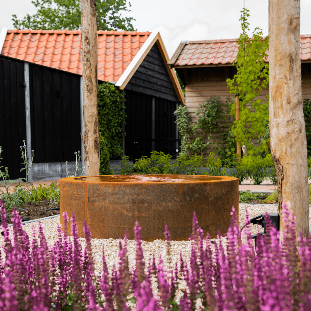 Cortenstaal waterschaal met fontein tussen paarse salvia in de belevingstuin in Langeveen