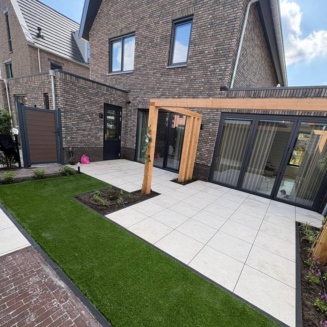 Kunstgras in L-vorm rond het keramische terras met composiet poort in Hengelo