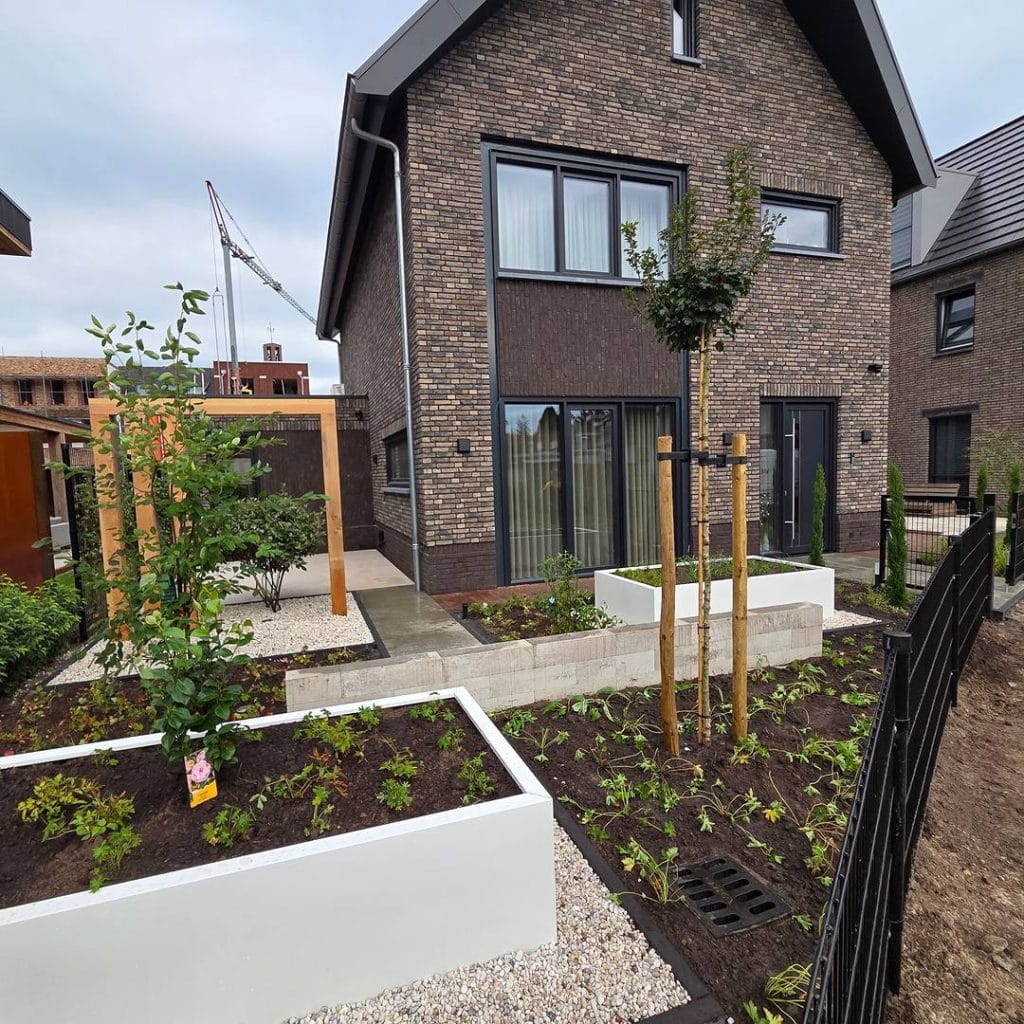 Voortuin met witte verhoogde bloembakken, grind en Douglas pergola bij nieuwbouwwoning in Hengelo