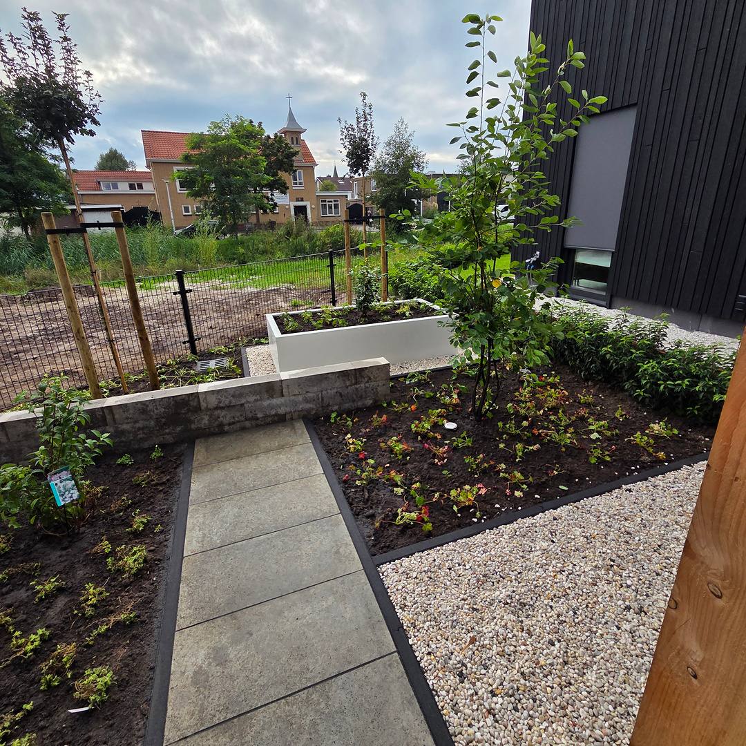 Pad van grijze tegels door grind en beplanting met dubbelstaafs hekwerk in Hengelo